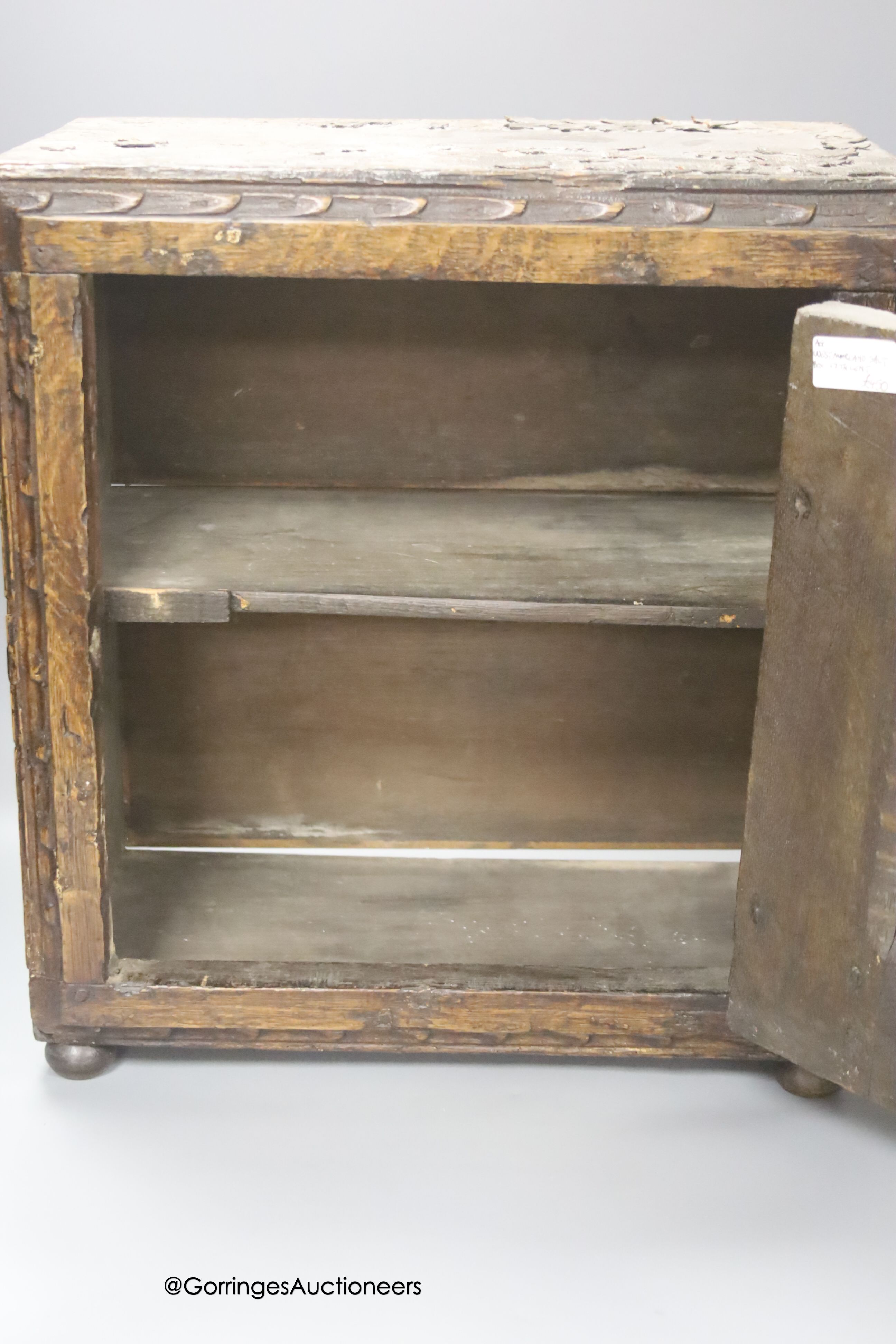 A small 17th century carved oak wall cabinet, enclosed by single panelled door with iron butterfly hinges, width 37cm